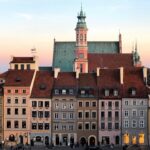 Blick auf Menschen, die in der Nähe und vor einem bunten Gebäude in Warszawa, Polen, spazieren gehen